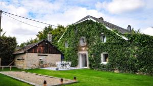 a house covered in ivy with a yard at L'anerie de Sourbrodt in Sourbrodt