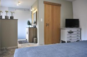 een slaapkamer met een bed en een dressoir met een televisie bij L'anerie de Sourbrodt in Sourbrodt +19 foto's