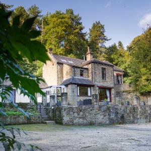 an old stone house with a stone wall at Highwood Lodge in Scissett