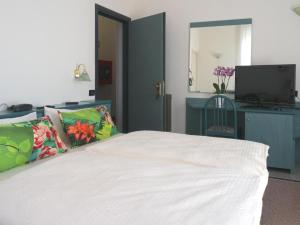 a bedroom with a white bed and a television at Hotel Flora in Celle Ligure