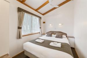 una camera da letto con un letto e due asciugamani di High Country Holiday Park a Mansfield