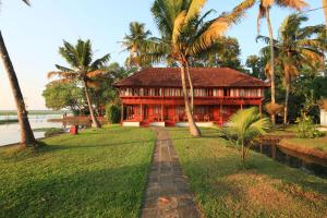 a house in the middle of a lawn with palm trees at Coconut Lagoon Kumarakom - A CGH Earth Experience in Kumarakom