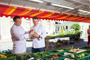 two men are standing under a tent with produce at Hotel Johannisbad in Bad Aibling
