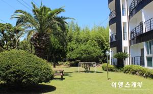 a park in front of a building with a bench and a goal at Toursketch Pension in Seogwipo