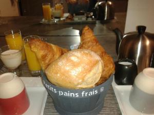 um cesto de pão sentado numa mesa com copos de sumo de laranja em Hotel La Marine, Vieux Port em La Rochelle