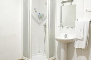 a white bathroom with a shower and a sink at Hostal Las Torres in Madrid