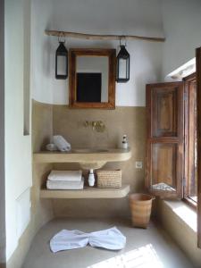a bathroom with a sink and a mirror and towels at Riad Matham in Marrakech