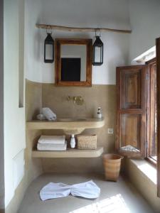 a bathroom with a sink and a mirror and towels at Riad Matham in Marrakesh