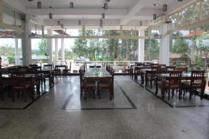 een eetkamer met tafels, stoelen en ramen bij Nexstay Coffee Grove Resort in Chikmagalūr