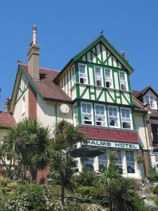 une grande maison verte et blanche avec des palmiers devant dans l'établissement The Palms Guest house, à Torquay