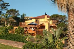 a large yellow house with a deck and chairs at Dutton's Cove Guest House in Herolds Bay