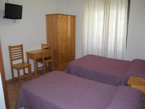 a bedroom with two beds and a table and a cabinet at Hostal Las Torres in Madrid