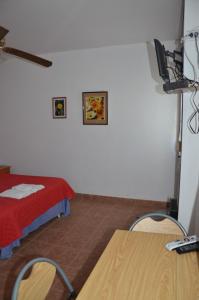 Zimmer mit einem Bett, einem Tisch und einem TV in der Unterkunft Nueve Lunas Chascomus in Chascomús