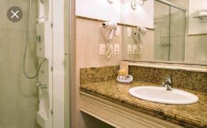 a bathroom with a sink and a mirror and a shower at Il Campanario Villaggio room in Florianópolis