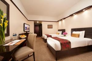 a hotel room with two beds and a desk at Millennium Hotel Sirih Jakarta in Jakarta