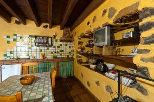 a kitchen with a table and a tv on a wall at Casa Rural Poblado Jirdana in La Torre