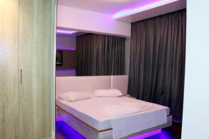 a bedroom with a white bed with purple lights at Hotel Praia Grande Niterói in Niterói