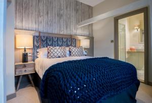a bedroom with a large bed with a blue blanket at The Cookie Jar in Alnwick