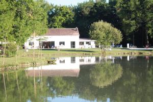 una casa blanca con un reflejo en un lago en Chalet de La Héronnière, en Chef-Boutonne
