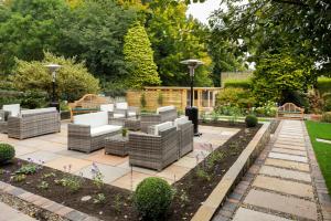a patio with wicker chairs and tables in a garden at The Cookie Jar in Alnwick