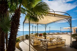 un patio con mesas y sillas y el océano en Hotel Kvarner - Liburnia, en Opatija