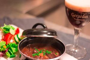 a pot of soup next to a glass of wine at Hotel Brasserie de Kroon in Gulpen