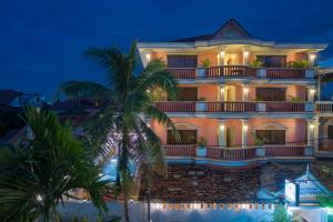 a large building with a palm tree in front of it at The Siem Reap Chilled Backpacker in Siem Reap