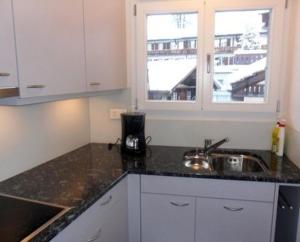 eine Küche mit einer Theke, einem Waschbecken und einem Fenster in der Unterkunft Pfaffenstöckli in Grindelwald