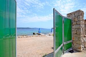 a green door on a beach with the ocean at House Merica in Drvenik Mali