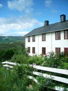 a white house with a fence in front of it at Dale Gård in Heggenes
