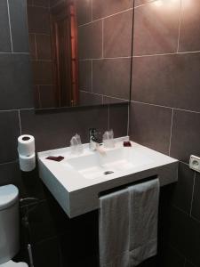 une salle de bain avec un lavabo blanc et un miroir dans l'établissement Hotel Arcos-Coruña, à Arcos de la Frontera