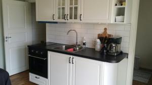 a kitchen with white cabinets and a sink at Sjönära Ullared in Ullared