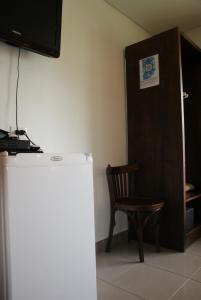 a room with a refrigerator and a chair and a door at Departamentos-Cabañas y Habitaciones Compartidas El Puente in El Calafate