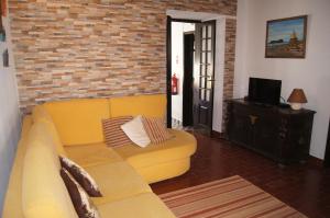 sala de estar con sofá amarillo y pared de ladrillo en Casa da Cancela, en Vila Franca do Campo
