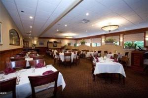 uma sala de jantar com mesas e cadeiras brancas e um restaurante em Winnapaug Inn em Westerly