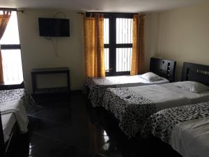 a hotel room with two beds and a television at Hotel Casa del Abuelo in Popayan