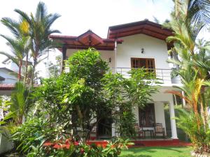 een huis met palmbomen ervoor bij Jungle Holiday Home in Hikkaduwa