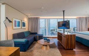 a hotel room with a couch and a bed and a tv at Hotel Luzeiros Recife in Recife