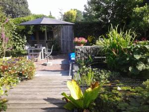 a garden with a wooden deck with a table and an umbrella at Bed and Breakfast de Verwennerij in Ermelo