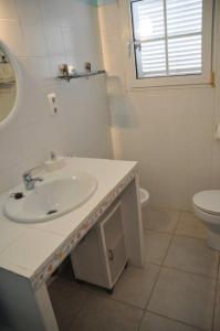 a white bathroom with a sink and a toilet at Casa a 50 metros del Mar in Oliva