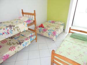 a room with three beds in a room at Pousada Canto Verde Itanhaém in Itanhaém