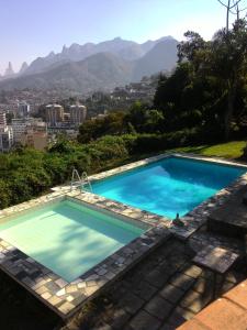 a swimming pool with mountains in the background at Hotel Philipp in Teresópolis