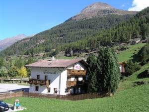 a building on a hill with mountains in the background at Haus Felsneck in Sölden