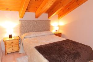 a bedroom with a bed and two night stands with lamps at Apartamentos Albá Casa Alquesera in Sahun