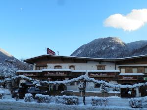 ein schneebedecktes Gebäude mit Bergen im Hintergrund in der Unterkunft Hotel Tiroler Stuben in Wörgl