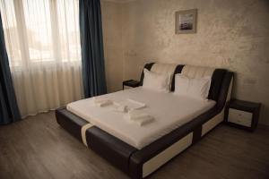 1 dormitorio con 1 cama con sábanas blancas y almohadas blancas en La Marcu Pensiune, en Tulcea