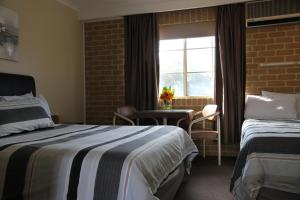 Un pat sau paturi într-o cameră la Grand Manor Motor Inn