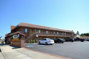 a building with a car parked in a parking lot at Santa Clarita Motel in Santa Clarita