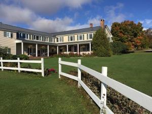 a white fence in front of a large house at Cooper Hill Inn in West Dover