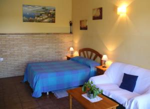 sypialnia z łóżkiem i kanapą w obiekcie Aparthotel Las Palomas w mieście La Puebla de los Infantes